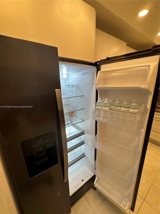 interior details featuring stainless steel fridge with ice dispenser, light tile patterned floors, and white cabinets