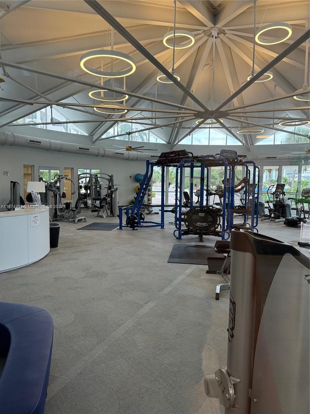 workout area featuring high vaulted ceiling, an inviting chandelier, and carpet flooring