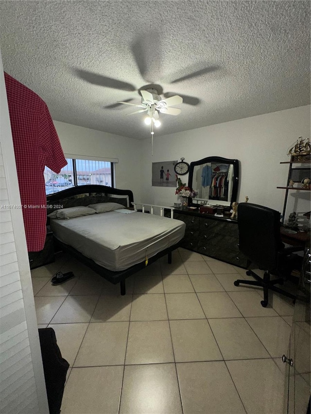 tiled bedroom with ceiling fan and a textured ceiling