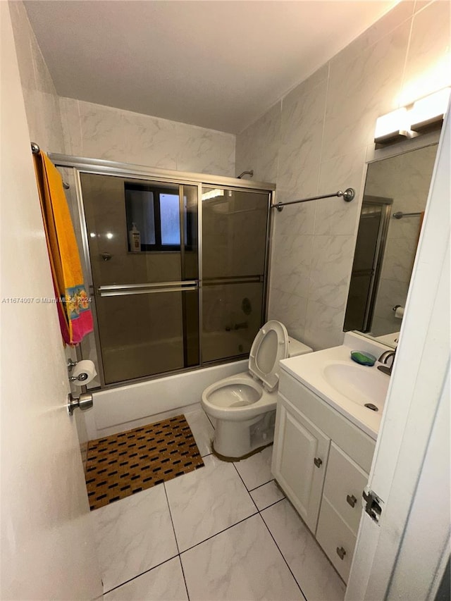 full bathroom with enclosed tub / shower combo, vanity, tile walls, and toilet