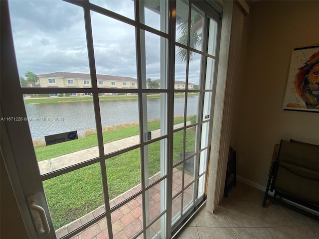 doorway with a water view, a healthy amount of sunlight, and tile patterned flooring