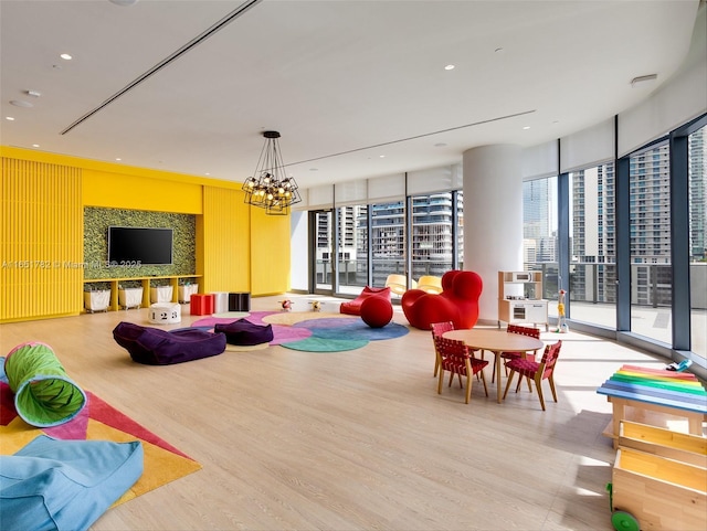 recreation room featuring expansive windows, hardwood / wood-style floors, and a notable chandelier