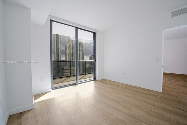 spare room featuring light hardwood / wood-style flooring and floor to ceiling windows