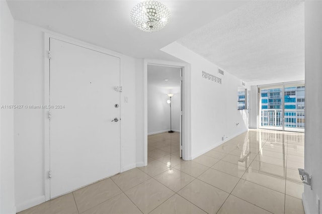 unfurnished room featuring a notable chandelier, expansive windows, light tile patterned floors, and a textured ceiling