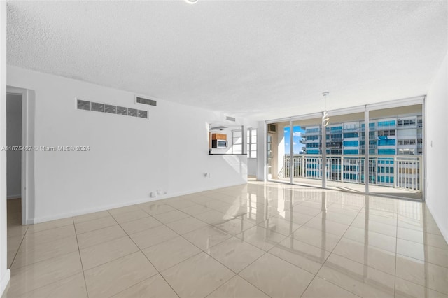 tiled spare room with floor to ceiling windows and a textured ceiling