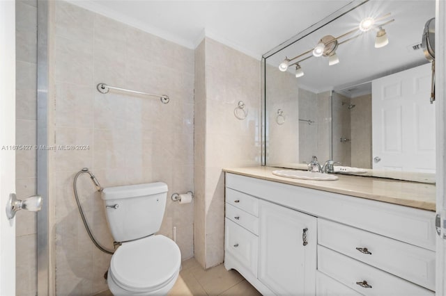 bathroom with tile patterned flooring, crown molding, toilet, vanity, and tile walls