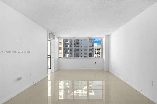 empty room featuring light tile patterned floors and a textured ceiling