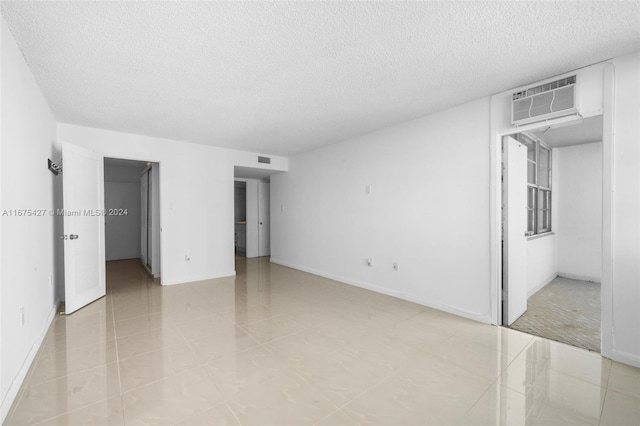 tiled empty room with a wall mounted AC and a textured ceiling