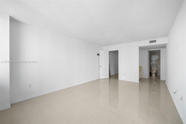 tiled empty room featuring a textured ceiling