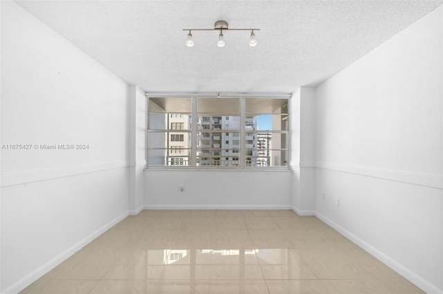 spare room with light tile patterned floors and a textured ceiling