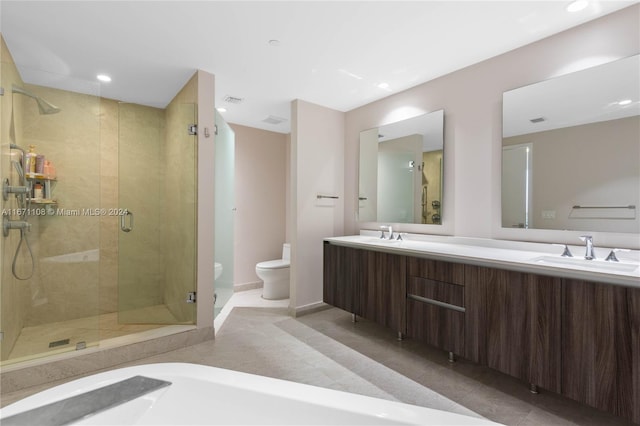 bathroom featuring vanity, toilet, a shower with door, and tile patterned floors