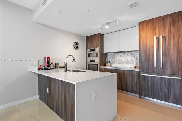 kitchen featuring sink, white cabinetry, fridge, double oven, and decorative backsplash