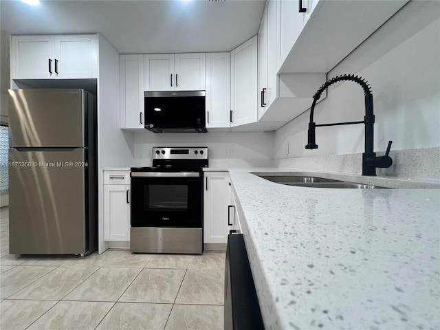 kitchen with stainless steel appliances, sink, light tile patterned floors, white cabinets, and light stone counters