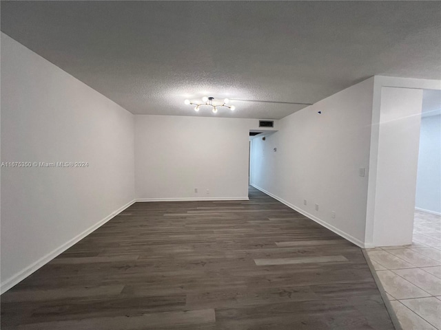 unfurnished room with a textured ceiling and dark hardwood / wood-style floors