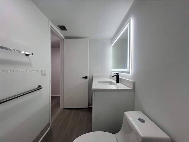 bathroom with vanity, toilet, and hardwood / wood-style flooring