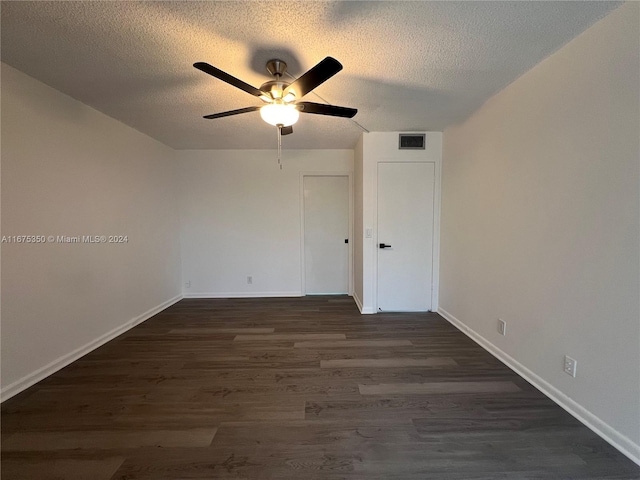 empty room with a textured ceiling, ceiling fan, and dark hardwood / wood-style flooring