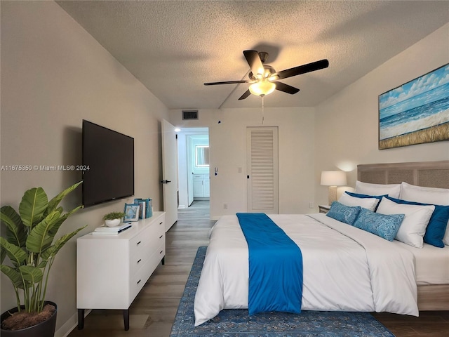 bedroom with dark wood-type flooring, ceiling fan, a closet, and a textured ceiling