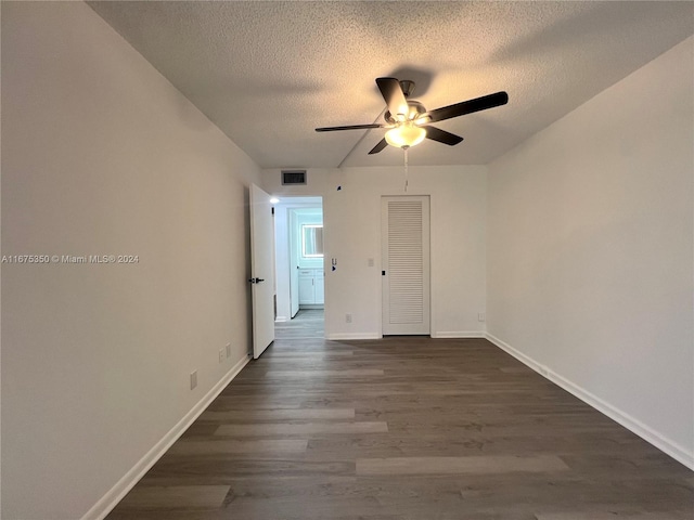 spare room with a textured ceiling, ceiling fan, and dark hardwood / wood-style flooring