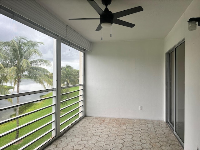 unfurnished sunroom featuring a water view and ceiling fan