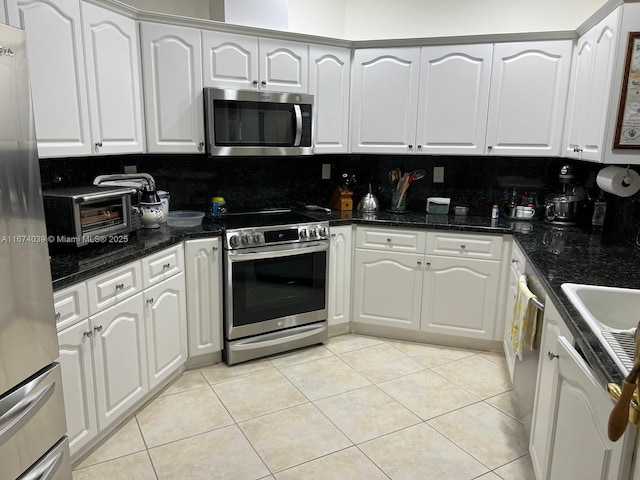 kitchen featuring backsplash, stainless steel appliances, white cabinetry, and light tile patterned flooring