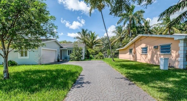 exterior space featuring driveway, a yard, an attached garage, and fence