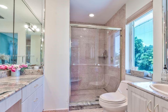 bathroom with walk in shower, vanity, toilet, and a wealth of natural light