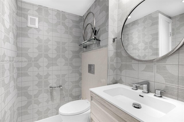 bathroom featuring vanity, toilet, tile walls, and backsplash