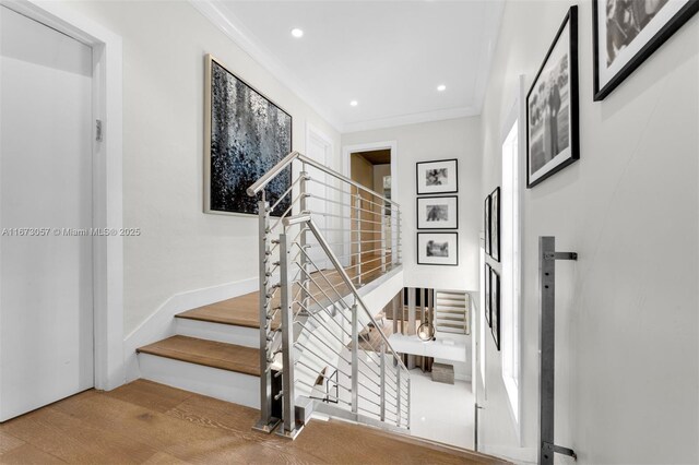 stairs featuring crown molding and hardwood / wood-style flooring