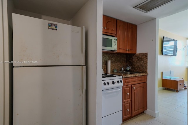 kitchen featuring white appliances, light tile patterned floors, visible vents, a sink, and tasteful backsplash