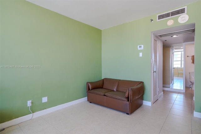 living room with light tile patterned floors, visible vents, and baseboards