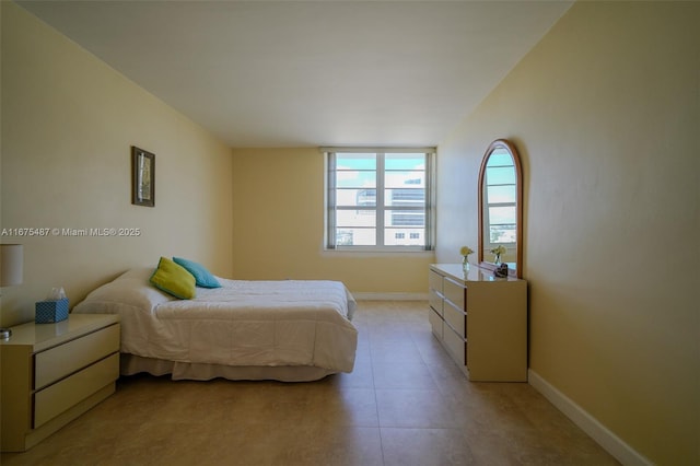 bedroom with light tile patterned floors and baseboards