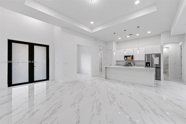 kitchen featuring white cabinets, a kitchen island, french doors, decorative light fixtures, and appliances with stainless steel finishes