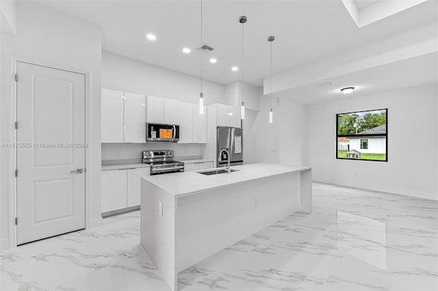 kitchen featuring sink, stainless steel appliances, hanging light fixtures, an island with sink, and white cabinetry