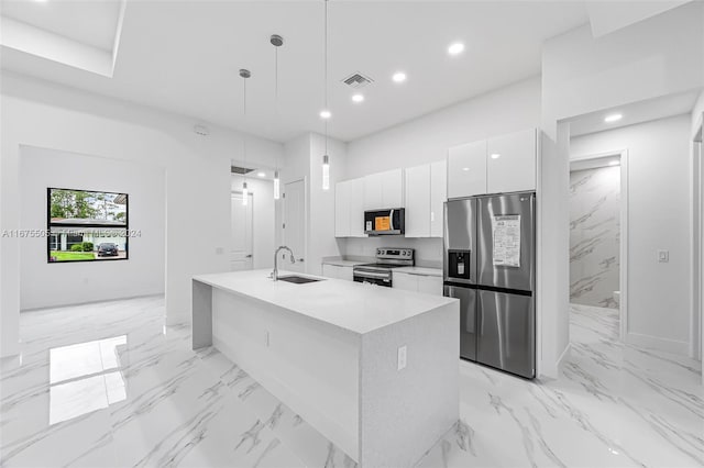 kitchen with stainless steel appliances, sink, hanging light fixtures, white cabinetry, and a center island with sink