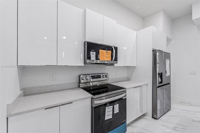 kitchen featuring light stone countertops, white cabinetry, and stainless steel appliances