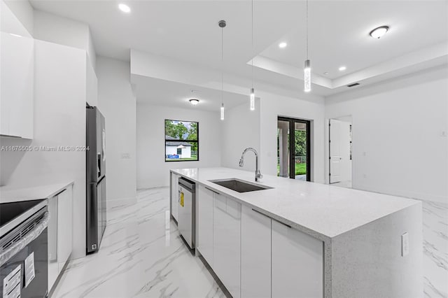 kitchen featuring a healthy amount of sunlight, hanging light fixtures, sink, and white cabinets