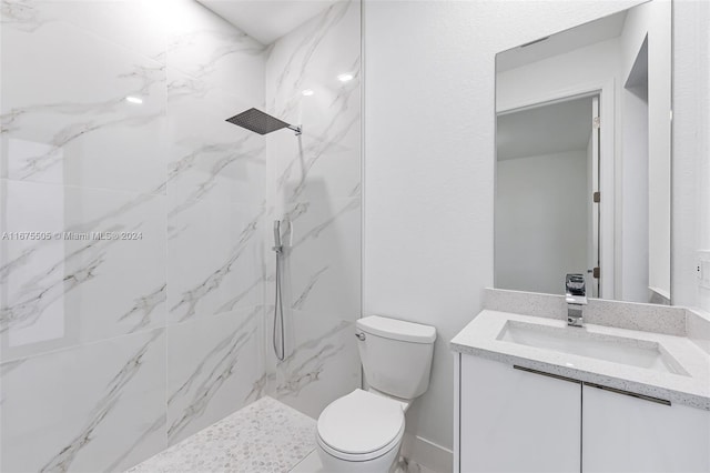 bathroom with vanity, toilet, and tiled shower