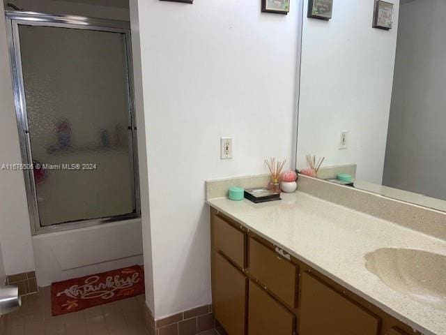 bathroom with bath / shower combo with glass door, tile patterned flooring, and vanity