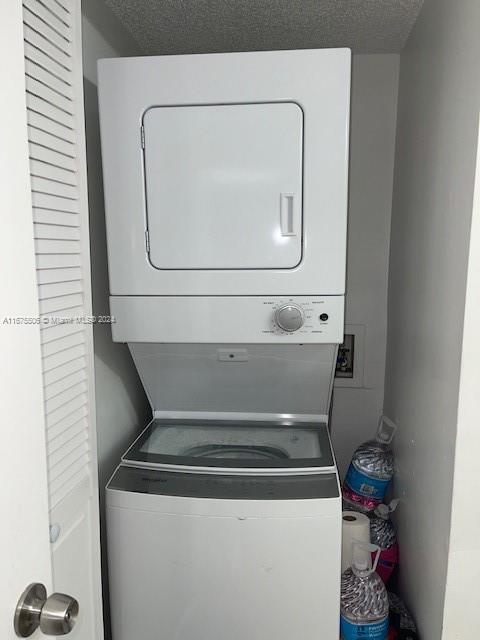 washroom featuring stacked washer and dryer and a textured ceiling