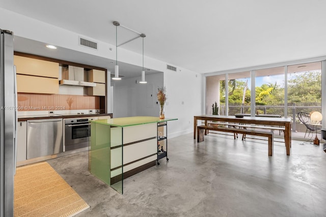 kitchen with wall chimney exhaust hood, decorative light fixtures, and appliances with stainless steel finishes