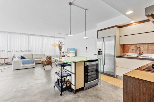 kitchen featuring stainless steel built in refrigerator, pendant lighting, sink, a kitchen island, and beverage cooler