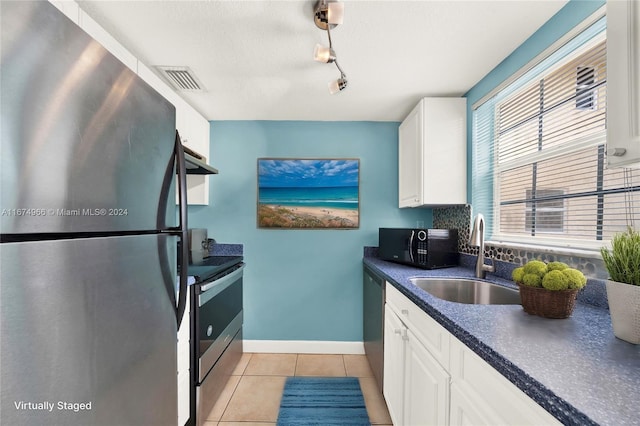 kitchen with light tile patterned floors, appliances with stainless steel finishes, sink, and white cabinetry