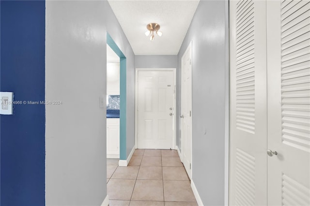 hallway with light tile patterned flooring and a textured ceiling