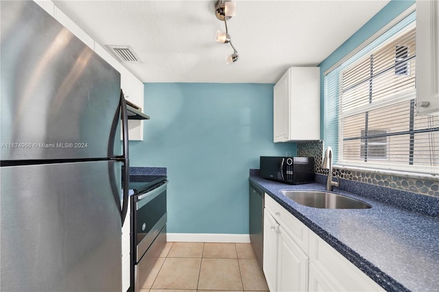 kitchen featuring light tile patterned flooring, appliances with stainless steel finishes, sink, and white cabinetry