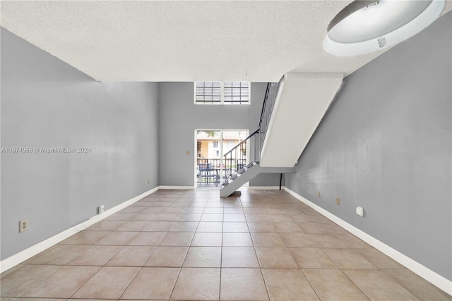 unfurnished living room featuring a textured ceiling and light tile patterned floors