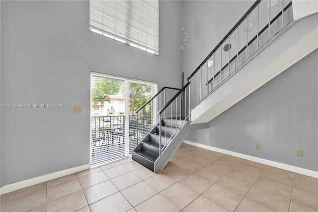 stairway with a towering ceiling and tile patterned flooring