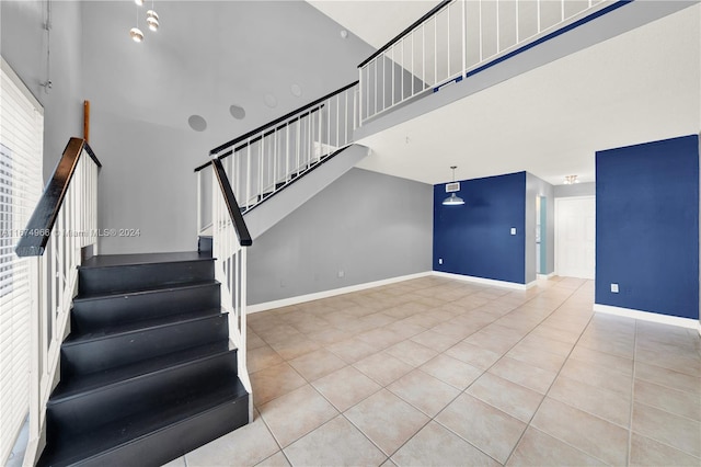 staircase with tile patterned floors and a towering ceiling