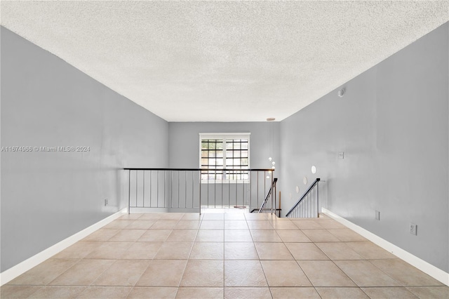 tiled empty room with a textured ceiling