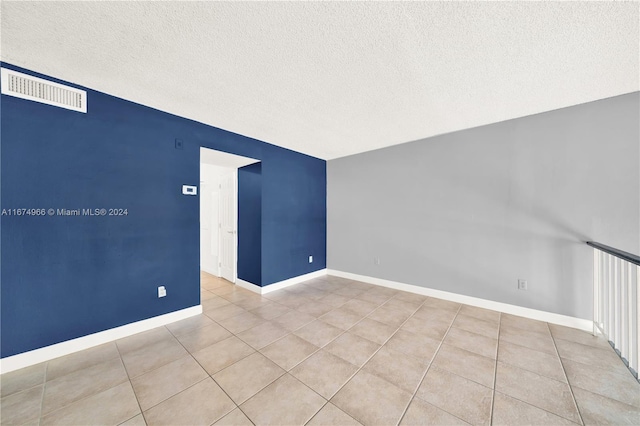 tiled empty room featuring a textured ceiling