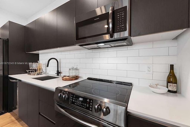 kitchen with stainless steel appliances, light hardwood / wood-style floors, decorative backsplash, and sink